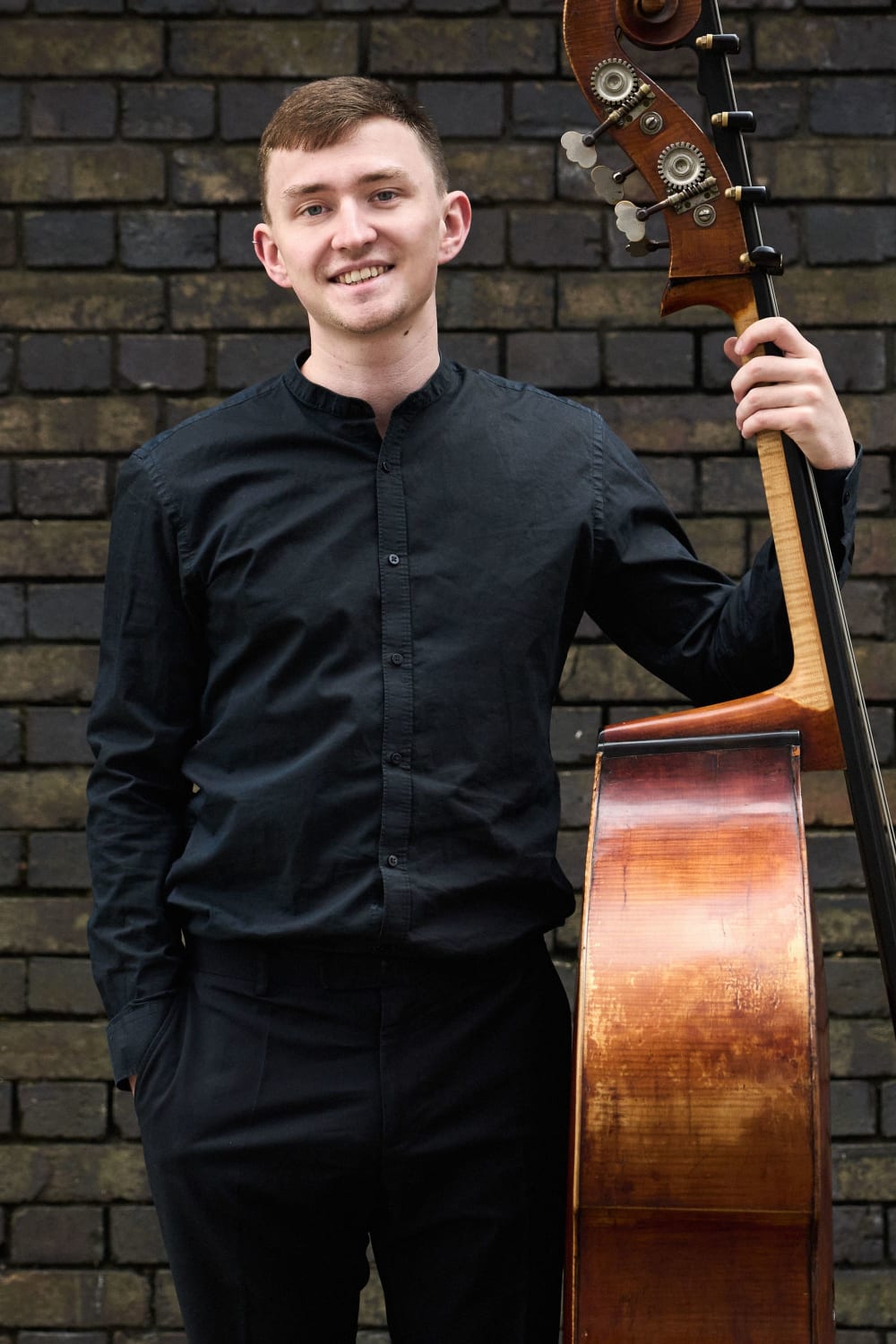 Will Duerden with double bass in front of wall