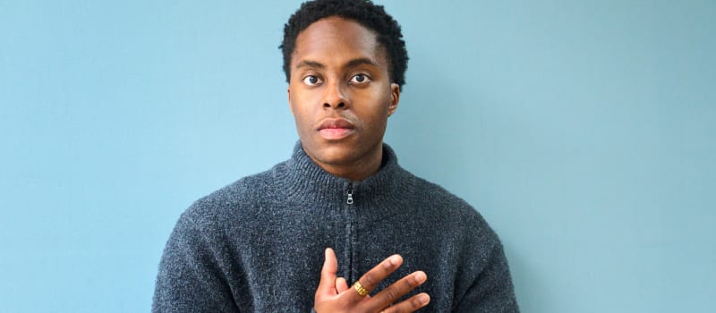 Amiri Harewood (pianist) in a dark blue jumper on a light blue background